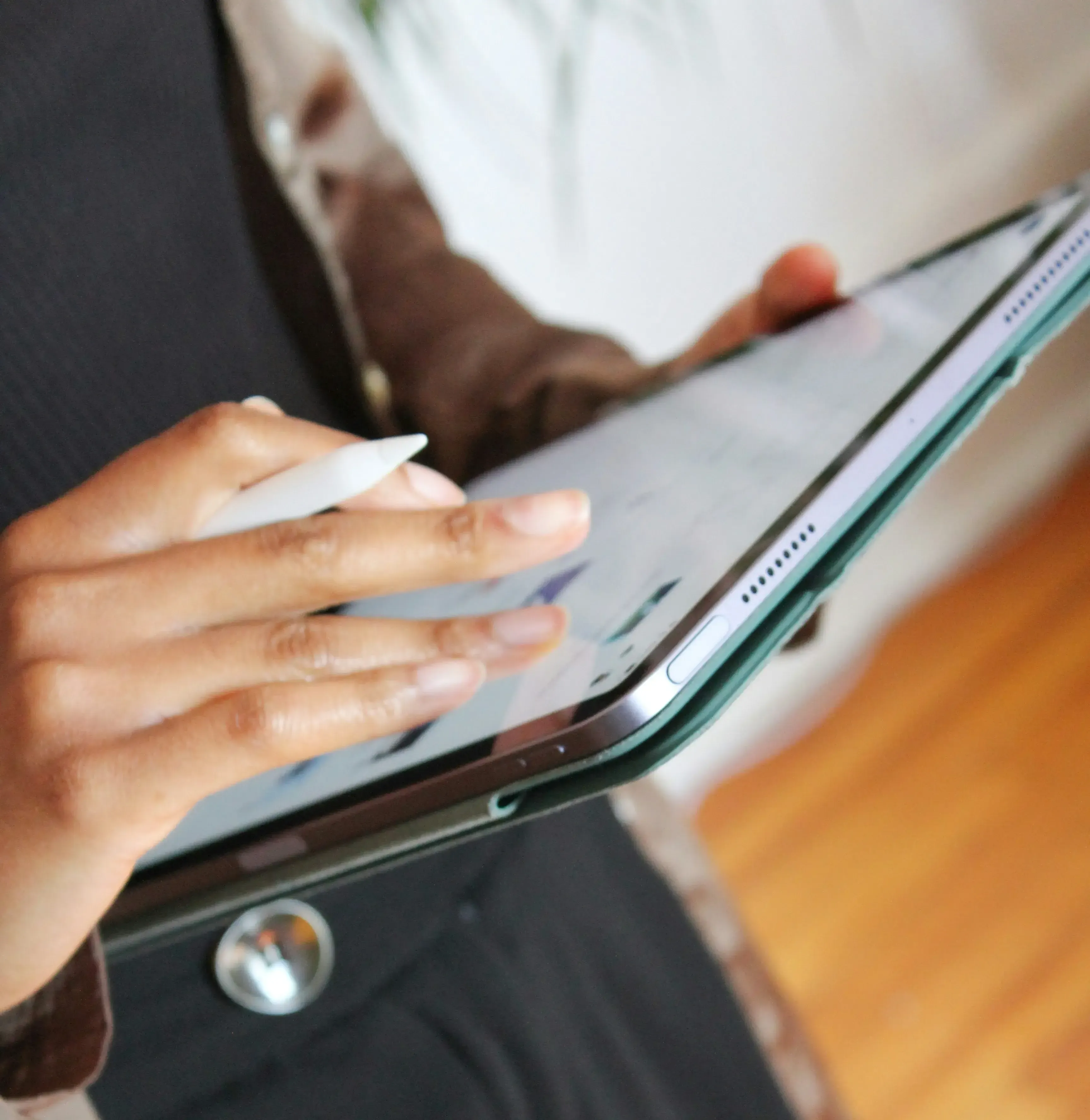 Person using a stylus on a tablet screen held in one hand.