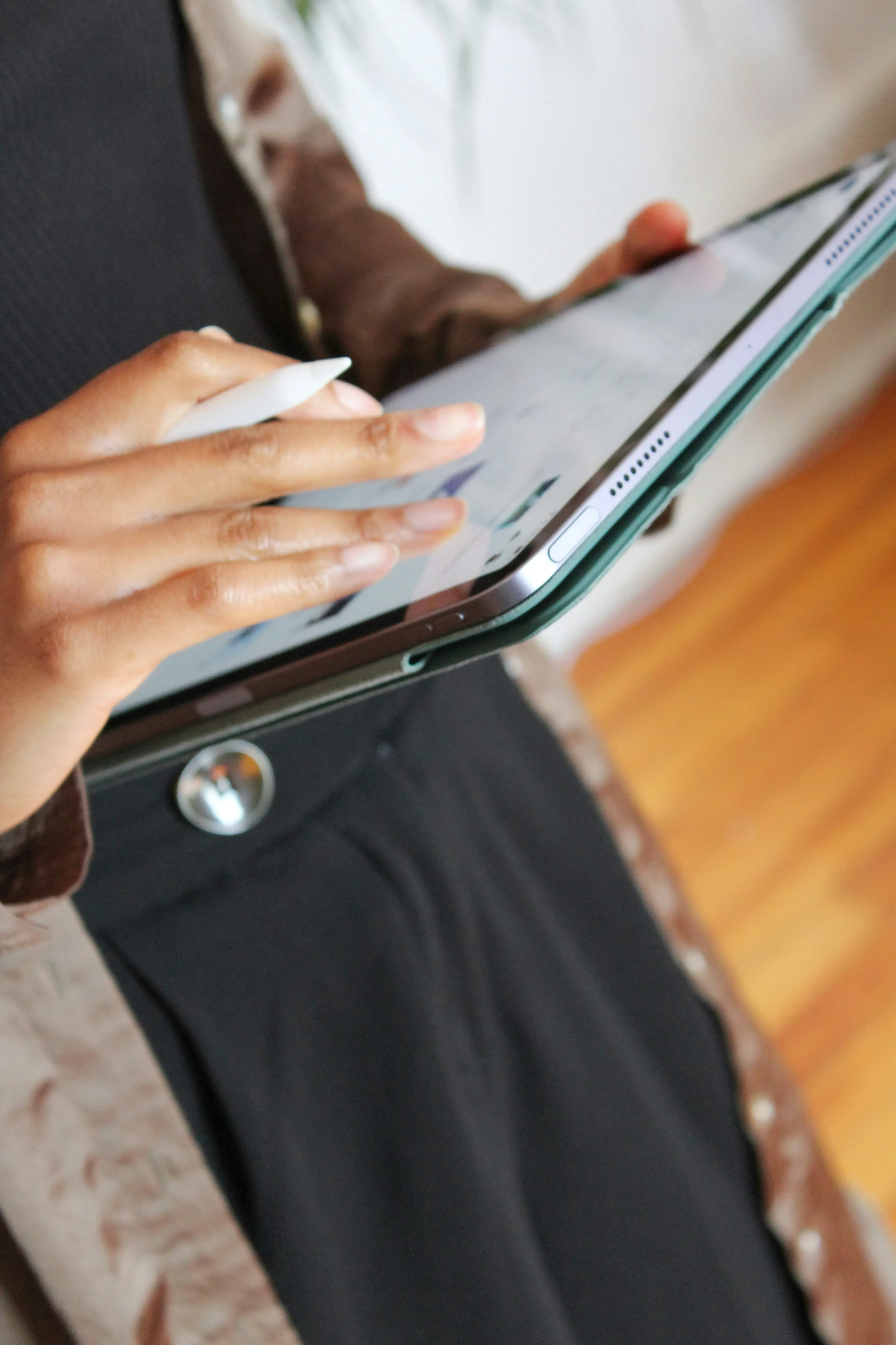 Person using a stylus pen on a tablet with a green case.